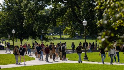 Dozens of students walk on sidewalks on the Blacksburg campus