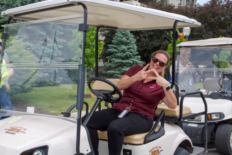 Lynsay Belshe makes the VT sign with her fingers while sitting in a golf cart outside of Lane Stadium